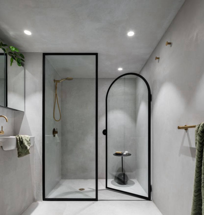 Light grey walls enclosed by a black-framed glass shower screen