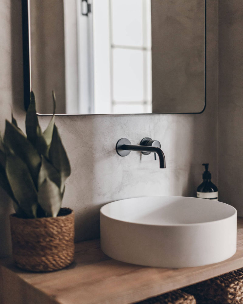 Grey wall behind a white round basin on a timber worktop