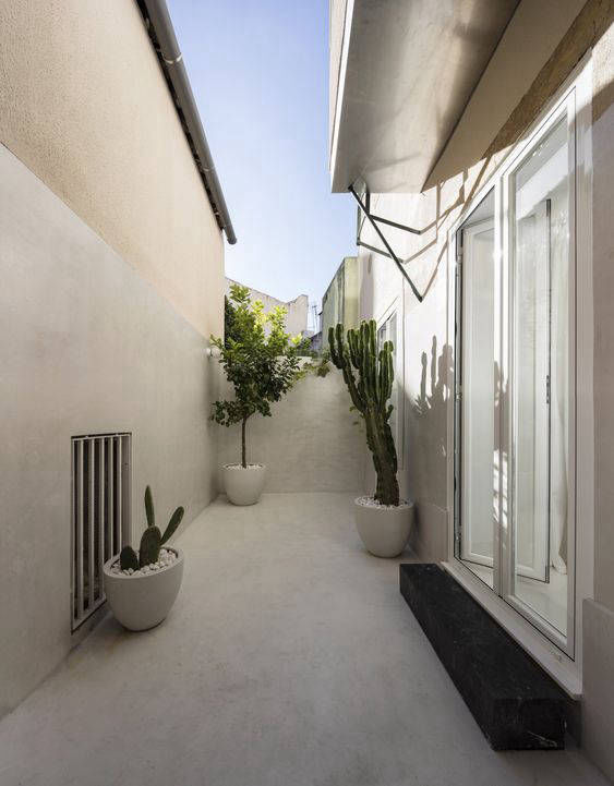 Narrow courtyard with planters between light-coloured walls