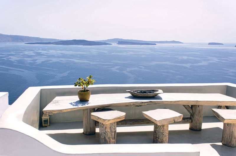Fixed light-coloured table and seating on a sea-view terrace