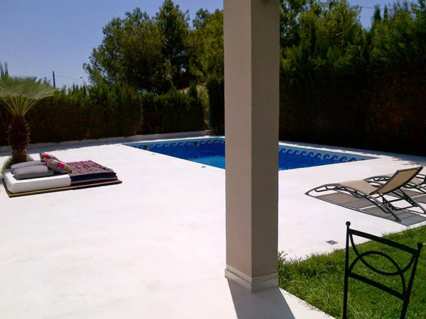 Light-coloured terrace flooring beside a pool with sun loungers