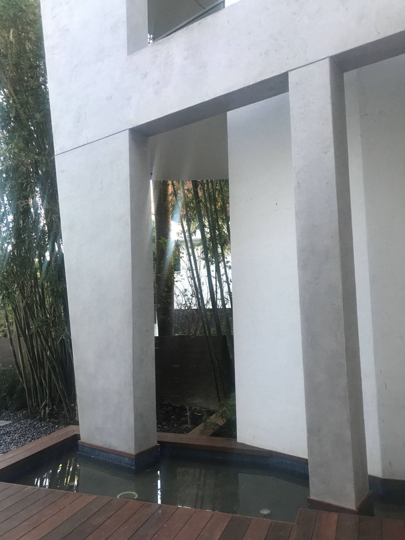 Shallow water feature and timber walkway in front of grey columns