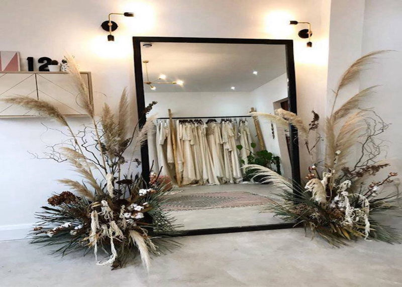 Grey retail flooring in front of a large mirror and dried plants
