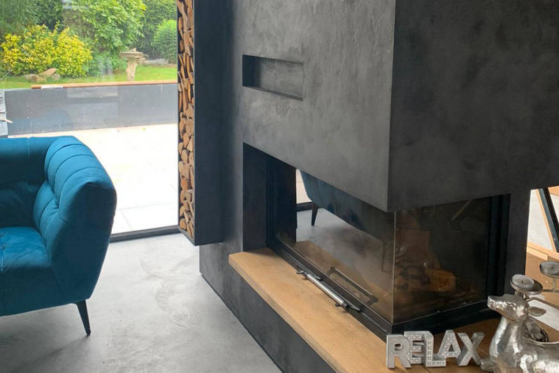 Dark grey corner fireplace finish beside a turquoise armchair