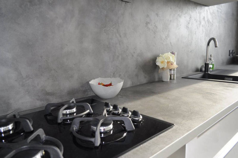 Grey worktop and wall with a black hob and sink