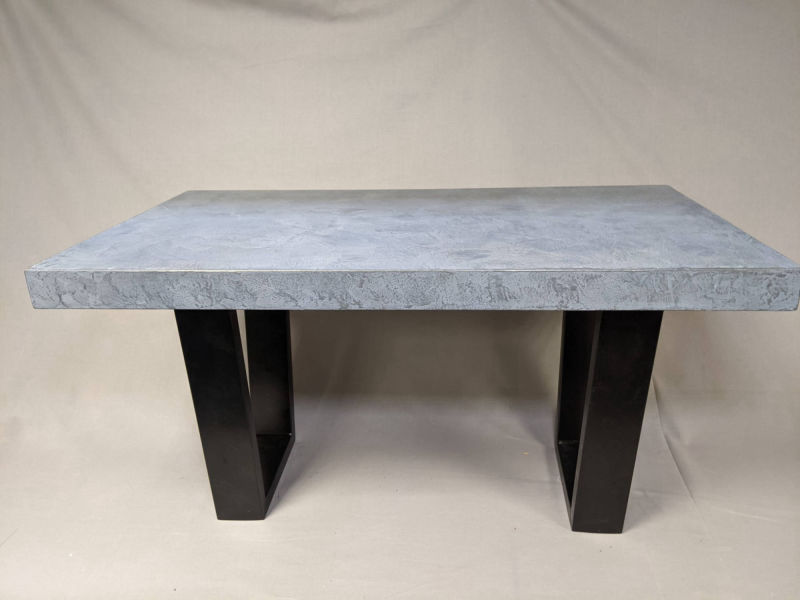 Rectangular grey table supported by wide black legs