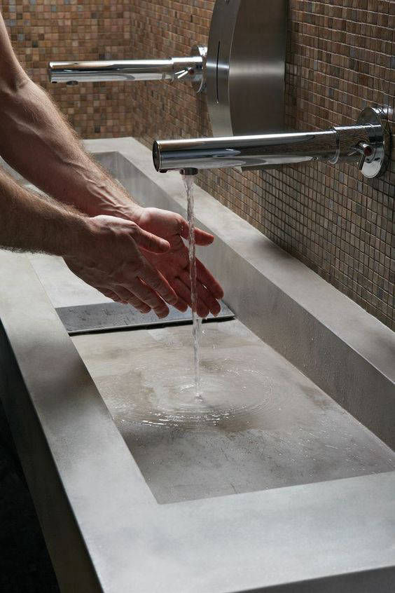 Long rectangular grey basin beneath wall-mounted taps