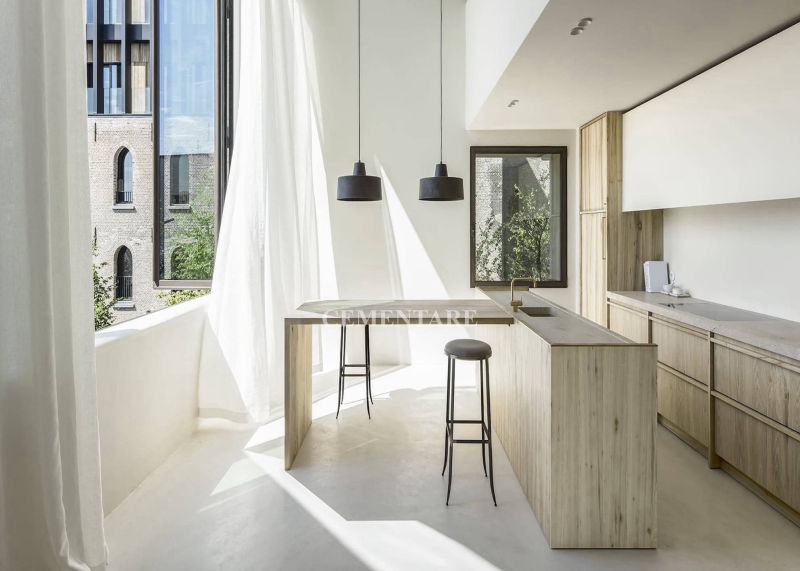 Light-coloured seamless flooring in a kitchen with timber cabinets and an island