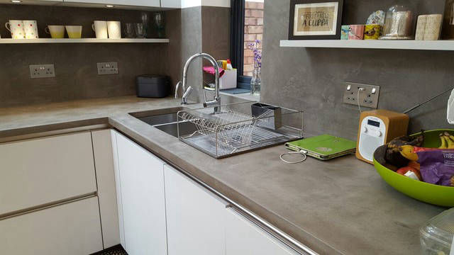 Grey kitchen worktop and wall around a metal sink