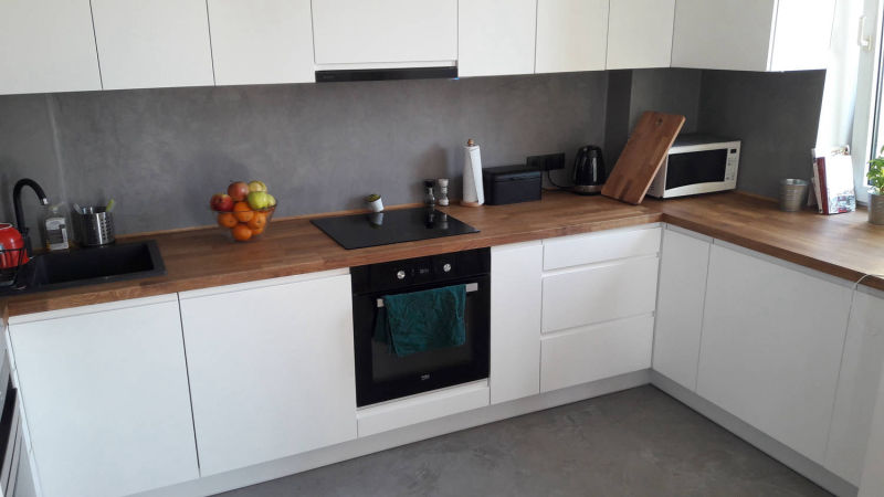 Grey wall behind a timber worktop in a white-cabinet kitchen