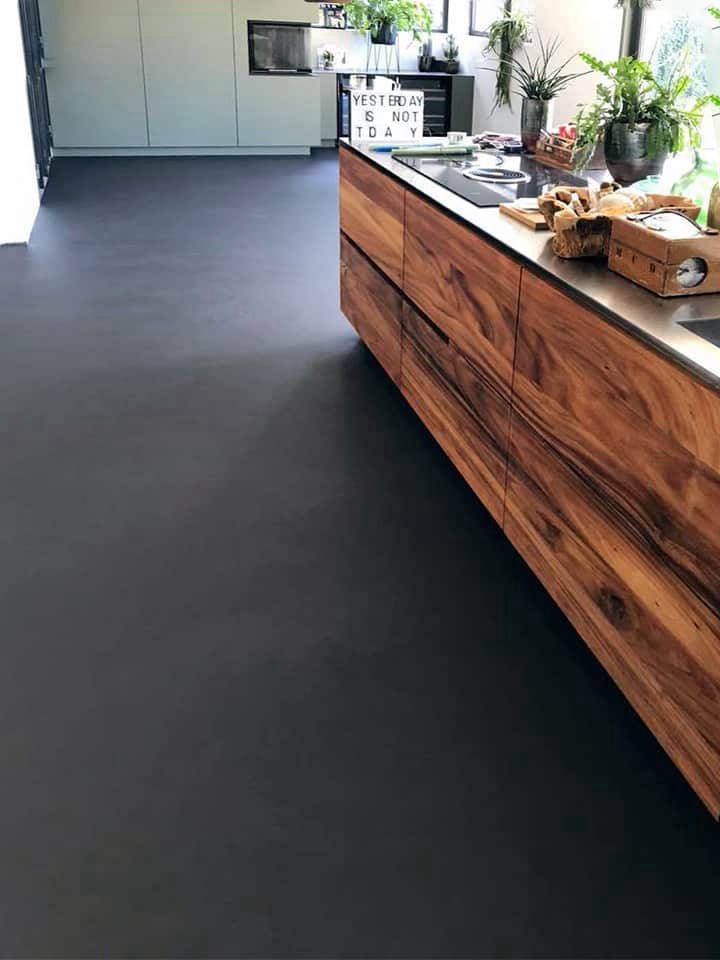 Dark grey flooring in a kitchen with timber cabinets