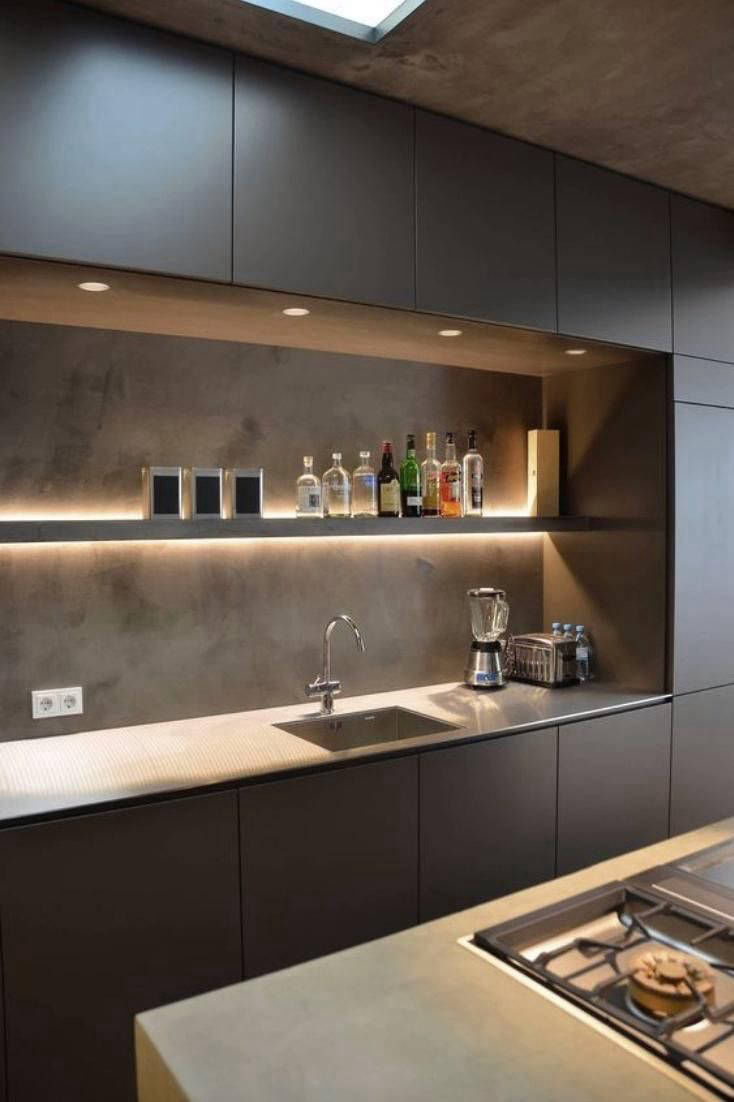 Illuminated splashback wall between dark kitchen cabinets