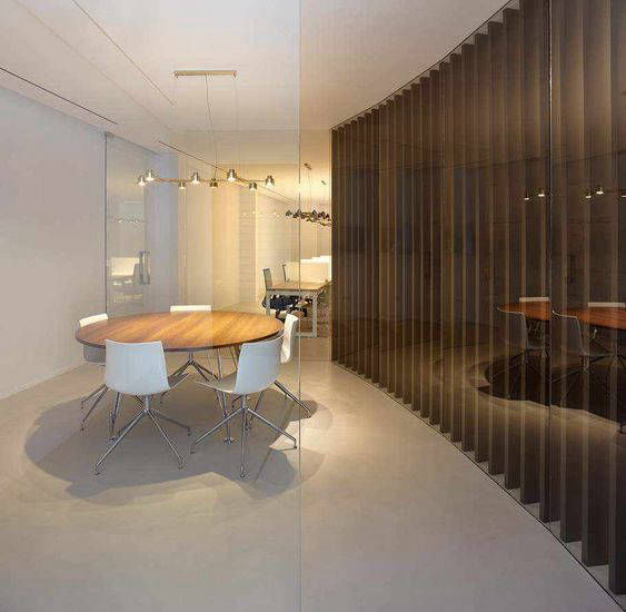 Round meeting table and light floor beside a vertical timber screen