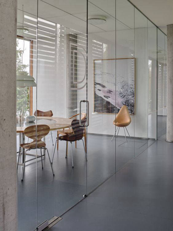 Dark grey flooring in a small glass-enclosed meeting room