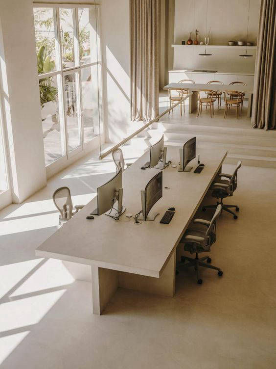 Long worktable and light-coloured floor in an office with large windows