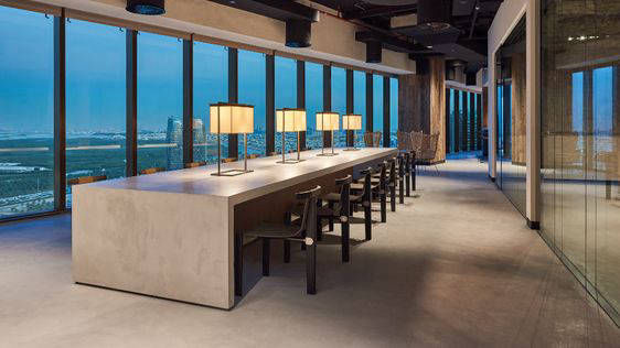 Long meeting table and grey flooring in front of glazing