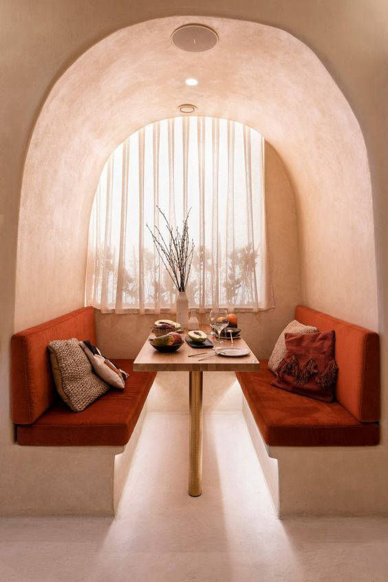 Opposing seats with orange cushions within an arched wall